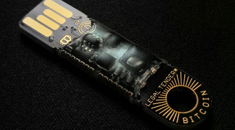 Hardware cold wallet resting on a laptop keyboard