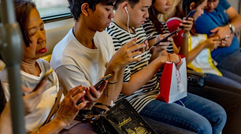 Young person isolated in a dark room looking at a smartphone representing the loneliness epidemic